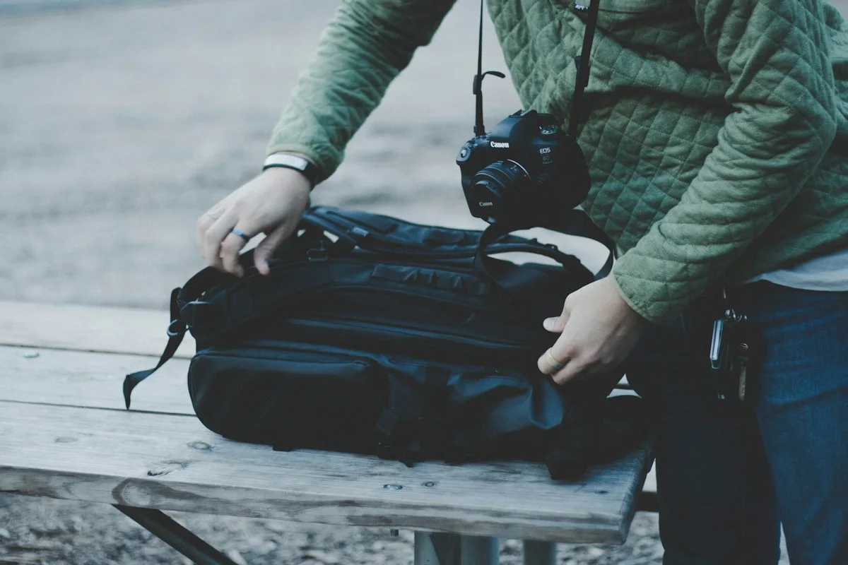 Traveler opening a dark duffel bag outdoors